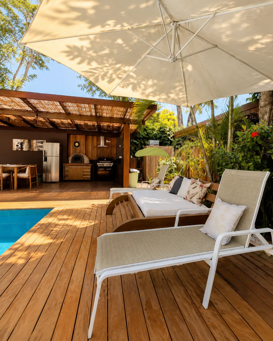 Deck com pergolado e espreguiçadeiras à beira da piscina privativa da Casa Paraíso