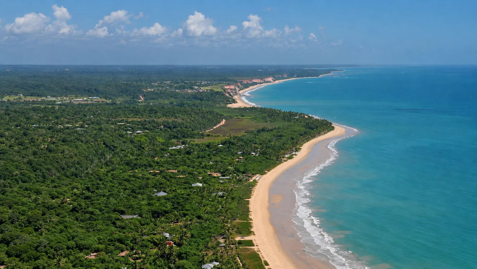 Vista aérea da orla de Arraial d'Ajuda, com barcos no mar esverdeado e casas entre os coqueiros